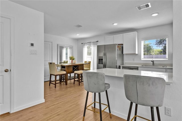 317 Riverwood Village Ln, Sealy, TX 77474 - kitchen featuring stainless steel fridge with ice dispenser, a breakfast bar area, a sink, white cabinets, and light countertops
