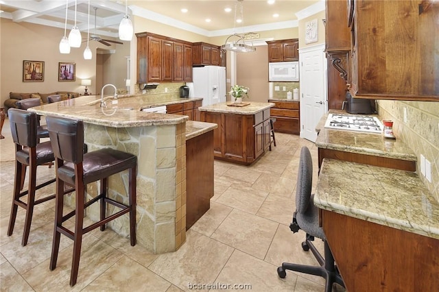 kitchen featuring white appliances, decorative backsplash, decorative light fixtures, kitchen peninsula, and a breakfast bar area