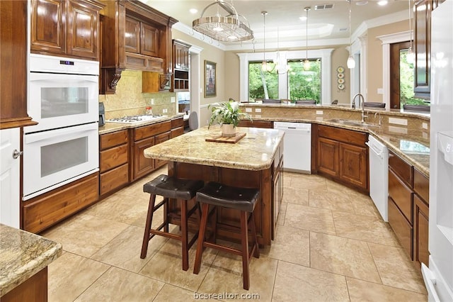 kitchen featuring a kitchen breakfast bar, white appliances, sink, pendant lighting, and a kitchen island