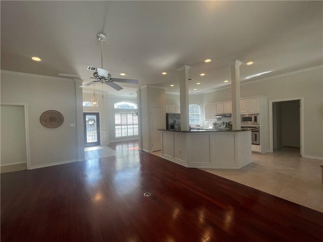 kitchen with ceiling fan, crown molding, appliances with stainless steel finishes, white cabinets, and decorative columns