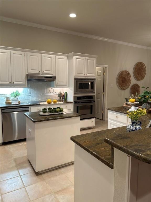 kitchen featuring a center island, white cabinetry, stainless steel appliances, tasteful backsplash, and ornamental molding