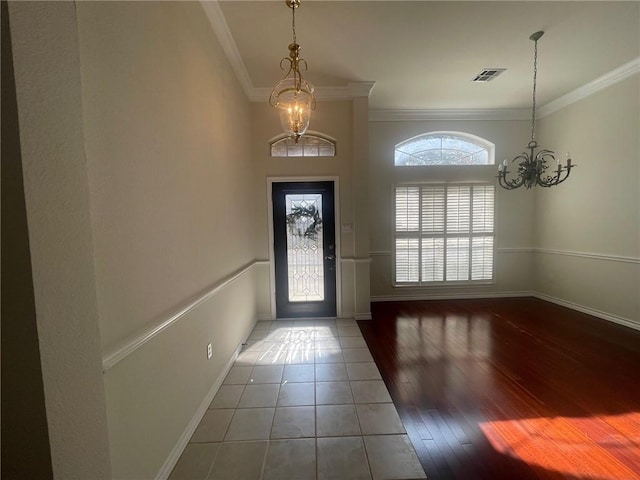 tiled foyer with crown molding and an inviting chandelier