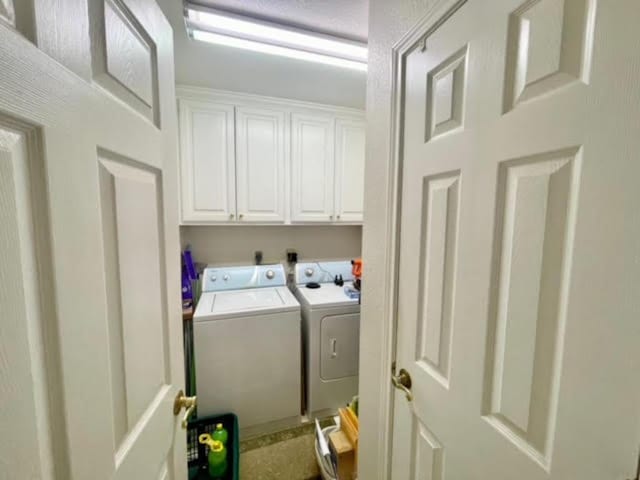 clothes washing area featuring cabinets and washing machine and clothes dryer