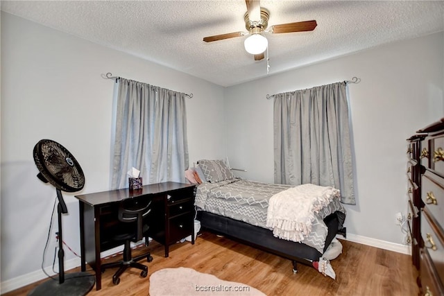 bedroom with a textured ceiling, light hardwood / wood-style flooring, and ceiling fan