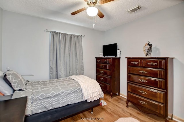 bedroom with a textured ceiling, light wood-type flooring, and ceiling fan