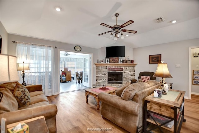 living room with ceiling fan, light hardwood / wood-style flooring, lofted ceiling, and a brick fireplace