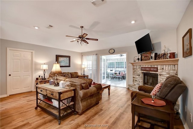 living room featuring a brick fireplace, ceiling fan, lofted ceiling, and light hardwood / wood-style flooring