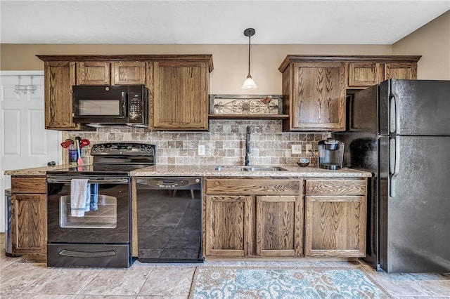 kitchen featuring backsplash, black appliances, sink, light stone countertops, and decorative light fixtures