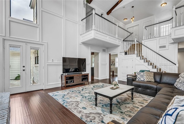 living room with beamed ceiling, dark hardwood / wood-style floors, a high ceiling, and french doors