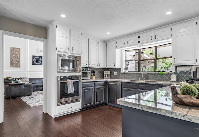 kitchen featuring white cabinetry, sink, light stone counters, dark hardwood / wood-style floors, and appliances with stainless steel finishes