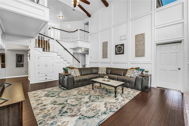 living room with beam ceiling, a towering ceiling, ceiling fan, and dark wood-type flooring