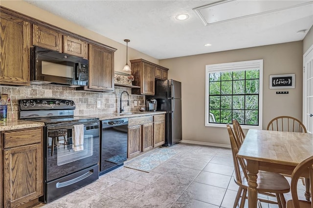 kitchen with light stone countertops, sink, tasteful backsplash, pendant lighting, and black appliances