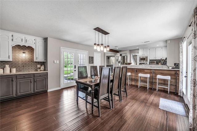 dining room with a textured ceiling, dark hardwood / wood-style floors, a notable chandelier, and sink