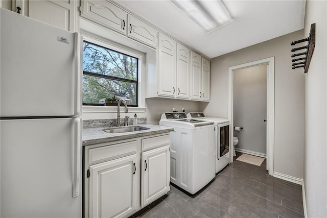 clothes washing area with washer and dryer, cabinets, and sink