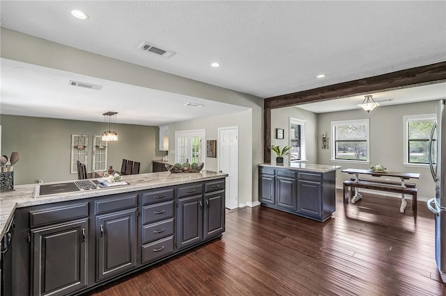 kitchen with light stone countertops, dark hardwood / wood-style flooring, beamed ceiling, pendant lighting, and stainless steel gas stovetop