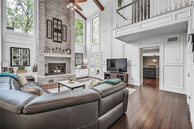 living room featuring high vaulted ceiling, ceiling fan, a fireplace, beam ceiling, and dark hardwood / wood-style flooring