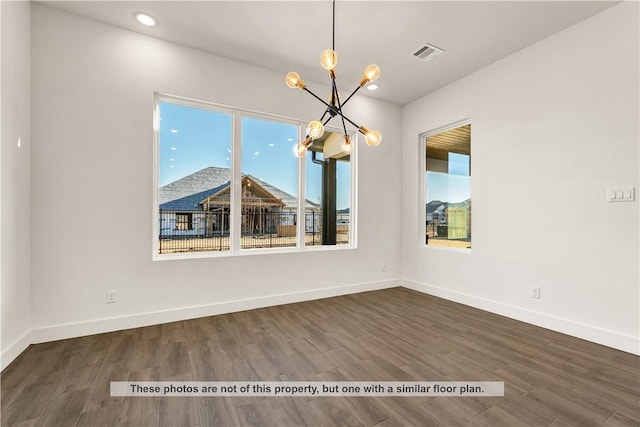 unfurnished dining area featuring dark wood-type flooring and an inviting chandelier