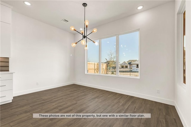 unfurnished dining area featuring an inviting chandelier and dark wood-type flooring