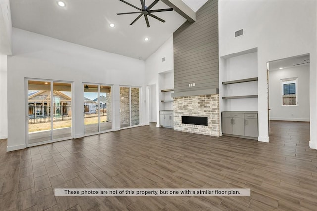 unfurnished living room featuring ceiling fan, a large fireplace, high vaulted ceiling, and dark wood-type flooring