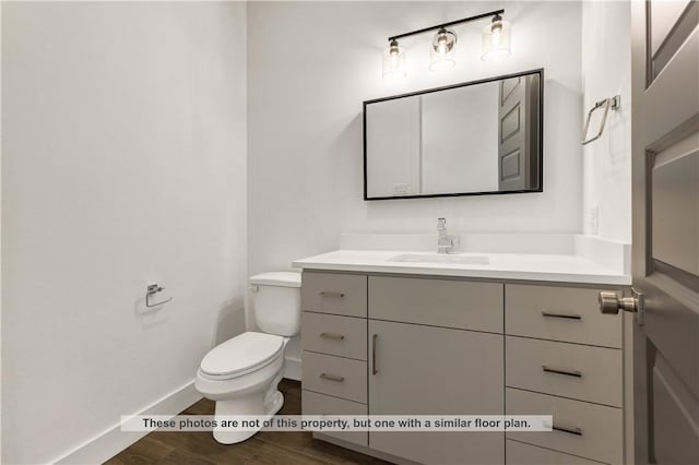 bathroom with hardwood / wood-style floors, vanity, and toilet