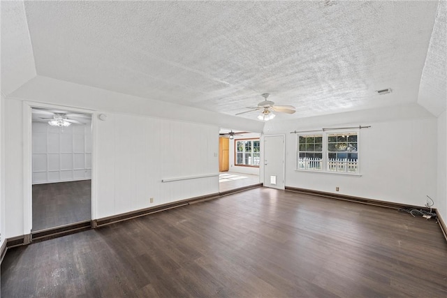 spare room featuring lofted ceiling, dark wood-type flooring, and a textured ceiling