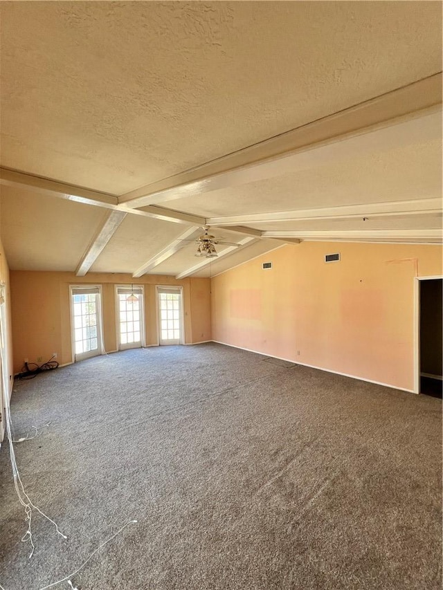 empty room with a textured ceiling, lofted ceiling with beams, and carpet