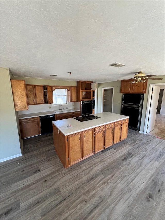 kitchen with open shelves, black appliances, a center island, and a sink