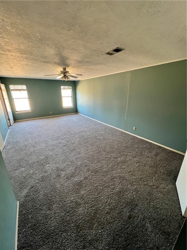 carpeted spare room with baseboards, a ceiling fan, visible vents, and a textured ceiling