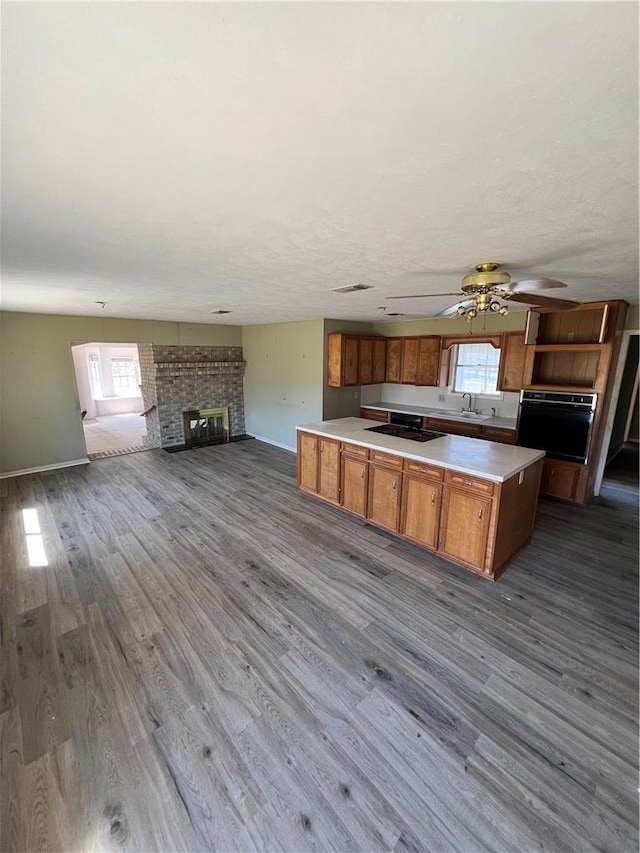 kitchen featuring black appliances, a brick fireplace, plenty of natural light, and brown cabinets