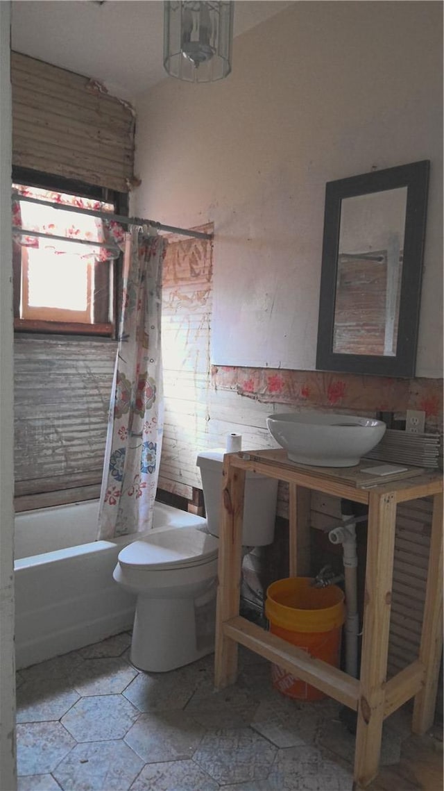 full bathroom with sink, shower / bathtub combination with curtain, and toilet