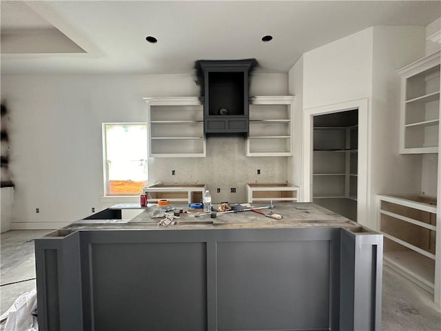 kitchen featuring open shelves, concrete flooring, gray cabinets, and a kitchen island