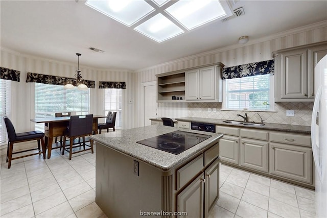 kitchen with backsplash, black appliances, sink, decorative light fixtures, and a kitchen island