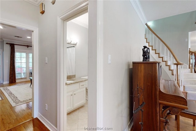 hallway with light hardwood / wood-style floors and crown molding