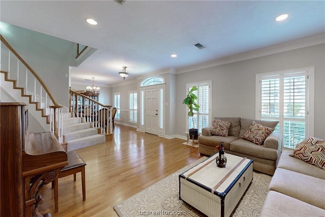 living room with light wood-type flooring, an inviting chandelier, and crown molding