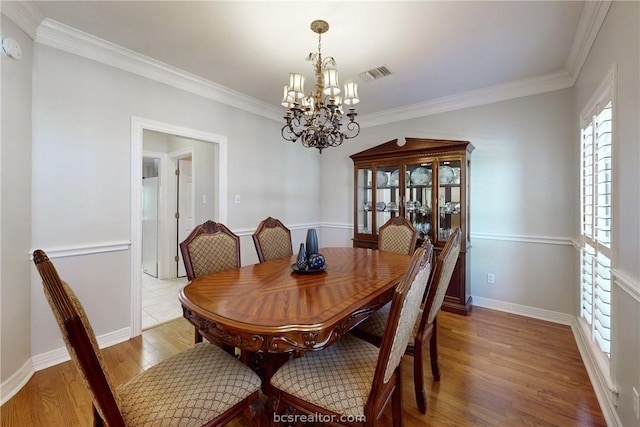 dining room featuring light hardwood / wood-style floors, crown molding, and a chandelier