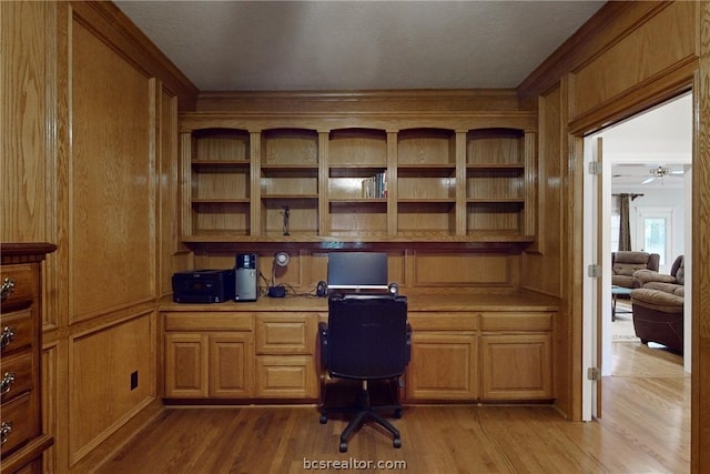 home office with ceiling fan, built in desk, light wood-type flooring, and a textured ceiling