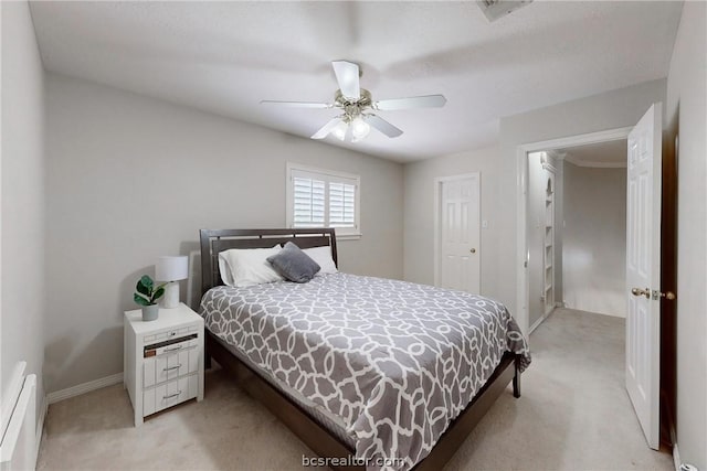 bedroom featuring baseboard heating, ceiling fan, a closet, and light colored carpet