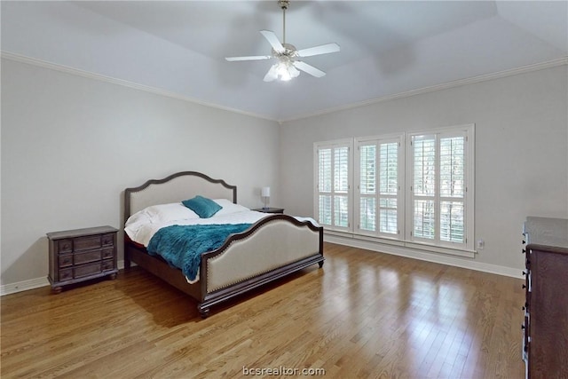 bedroom featuring ceiling fan, a raised ceiling, crown molding, and light hardwood / wood-style flooring