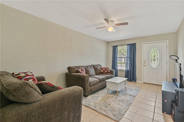 living room featuring light tile patterned floors, a textured ceiling, and ceiling fan