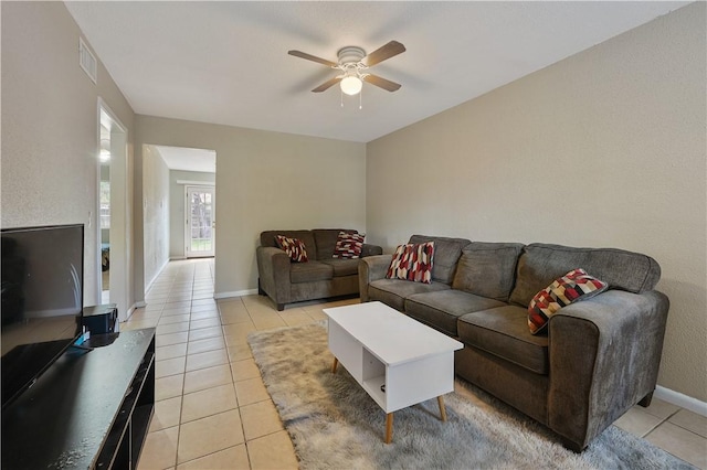 living area featuring light tile patterned floors, baseboards, visible vents, and ceiling fan
