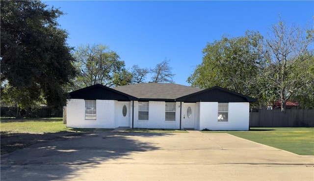 ranch-style home with driveway, fence, and a front yard