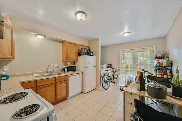 kitchen featuring a textured ceiling, sink, light tile patterned flooring, and white appliances