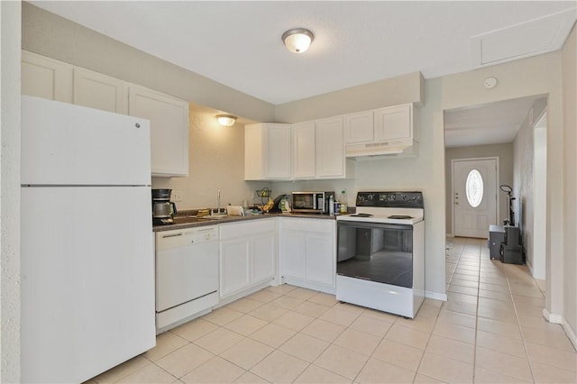 kitchen featuring white appliances, light tile patterned flooring, under cabinet range hood, white cabinetry, and dark countertops