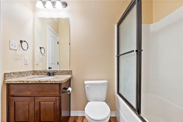 full bathroom with toilet, vanity, wood-type flooring, and combined bath / shower with glass door