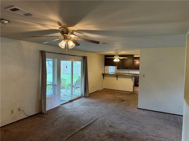 unfurnished living room with carpet, a textured ceiling, and ceiling fan