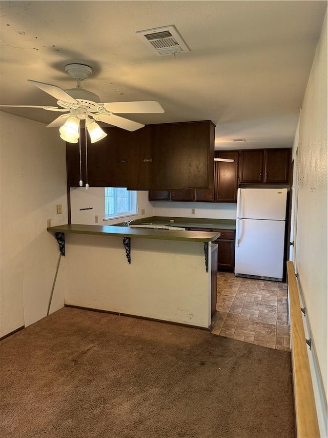 kitchen featuring light carpet, white refrigerator, ceiling fan, a kitchen bar, and kitchen peninsula