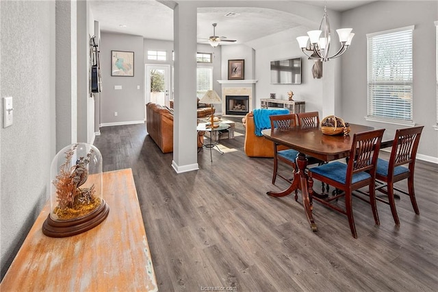 2025 Jester Trl, Bryan, TX 77807 - dining room featuring ceiling fan, arched walkways, wood finished floors, a fireplace with raised hearth, and a chandelier