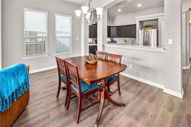 dining room featuring sink, hardwood / wood-style floors, and an inviting chandelier