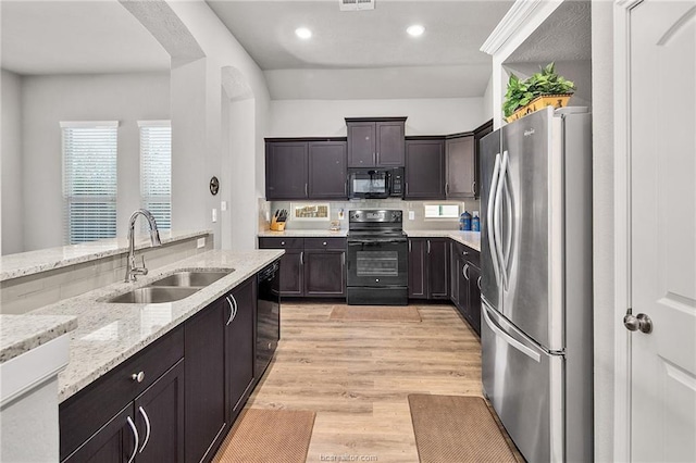 2025 Jester Trl, Bryan, TX 77807 - kitchen featuring black appliances, light stone countertops, light wood-style flooring, recessed lighting, and dark brown cabinetry