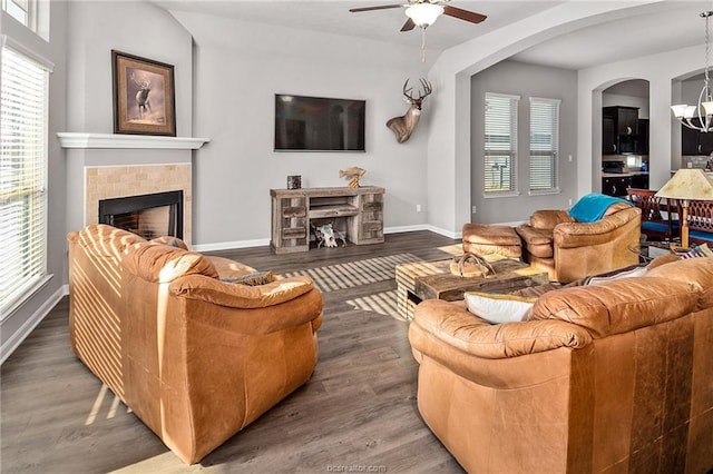 living room featuring a wealth of natural light, a fireplace, wood-type flooring, and ceiling fan with notable chandelier